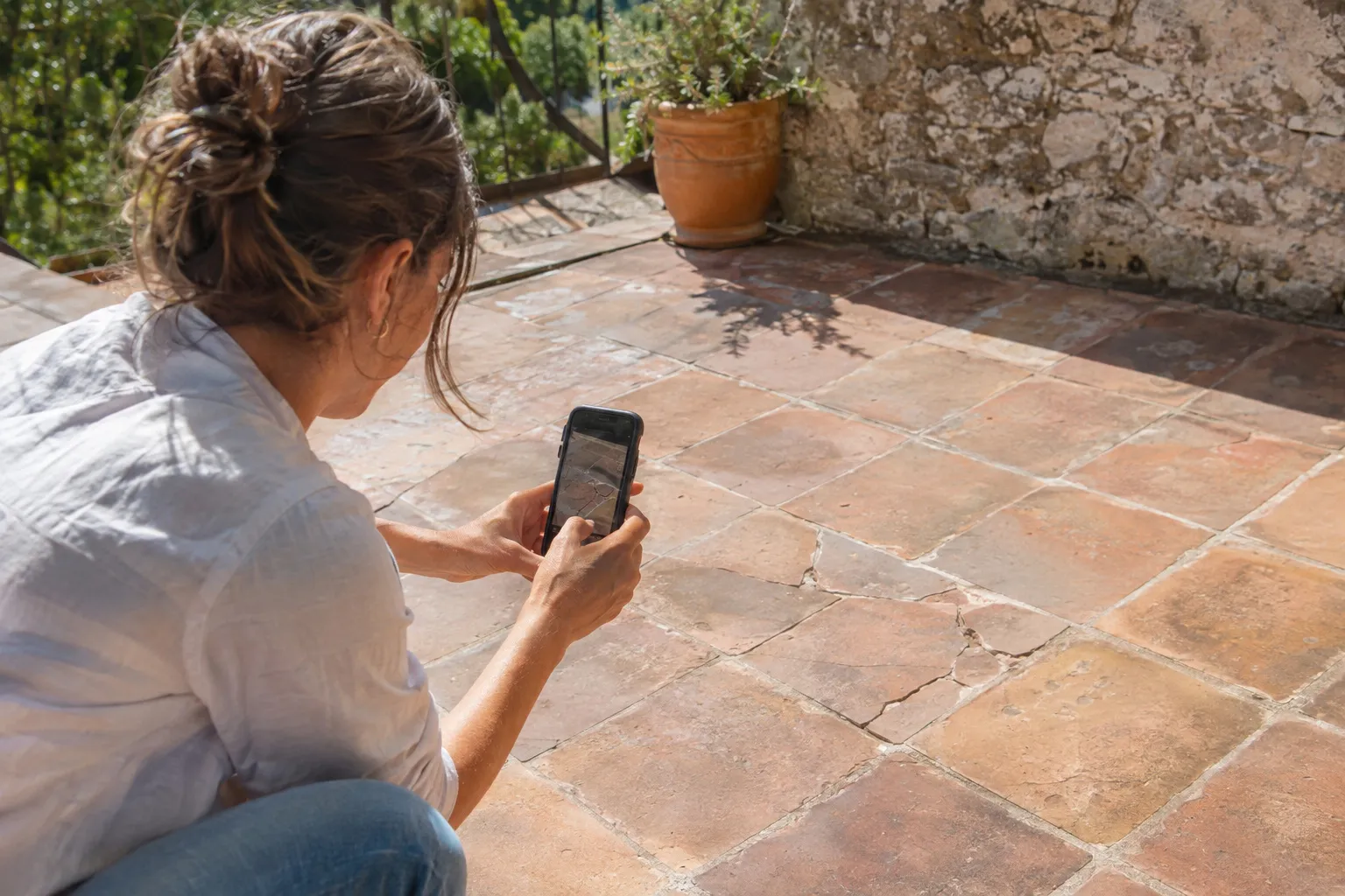 Une propriétaire photographie son ancien carrelage avec un téléphone pour demander un devis